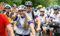 Radfahrergruppe mit winkender Frau im Vordergrund